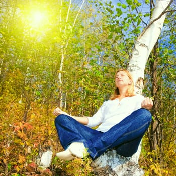 Woman meditating on the birch tree