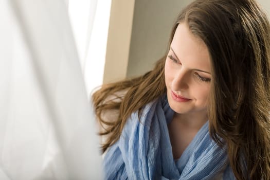 Young woman next to window looking down romantic pure portrait