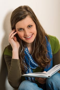 Portrait of student teenager woman with book listen music