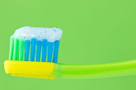toothbrush with toothpaste isolated on green background