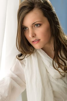 Beautiful thoughtful woman in white looking out of window