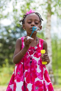 Portrait of a cute african american little girl blowing soap bubbles