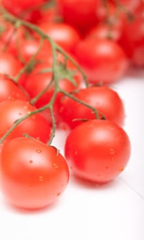 Closeup of Bunch of Fresh Cherry Tomatoes on White Table