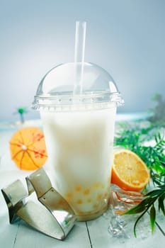 Milky bubble tea blended with fresh orange fruit and boba or tapioca balls served at the sea