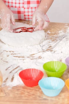 a little girl is cooking the dough for making biscuits