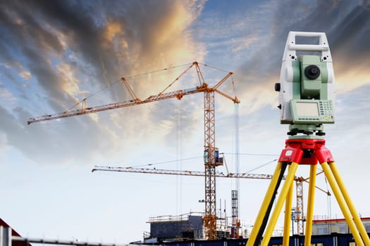 large measuring instrument, total-station, with sunlit building site in background, conceptual image