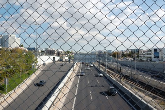 Cars on the motorway and chain link fence. City traffic.