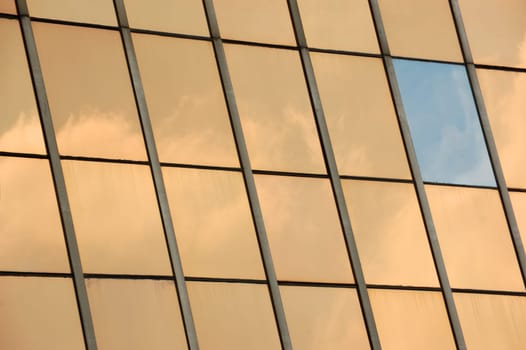 Sky reflected on glass facade panel of a modern building. Abstract background.