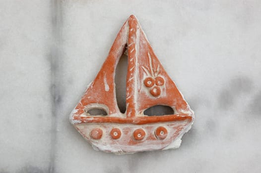 Small ceramic boat with sails. Traditional pottery on marble background.