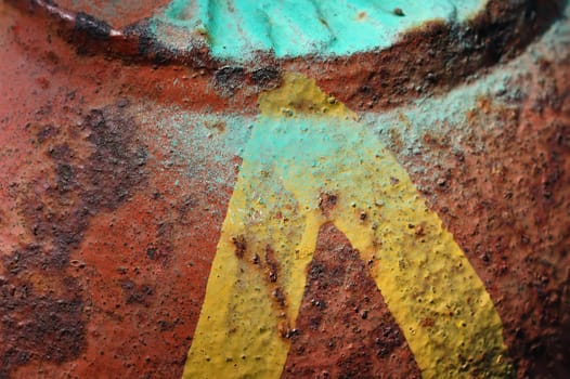 Yellow arrow on peeling rusty metal surface. Abstract iron background texture.