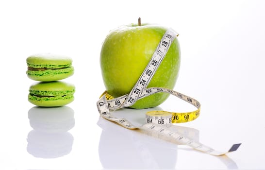 Apple, macarons and measuring tape. Concept of nutrition