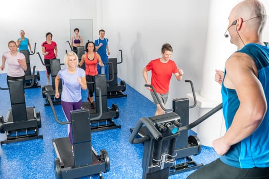 Alpinning class of young adults with fitness personal trainer