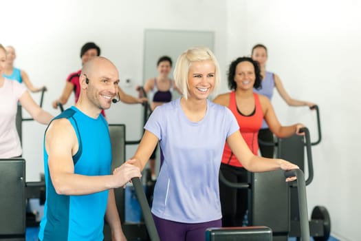 Fitness instructor with gym people exercise on cross-trainer
