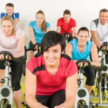 Fitness group of people on bicycle doing spinning at gym