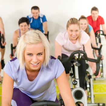 Fitness young woman on gym bike spinning indoor cardio exercise