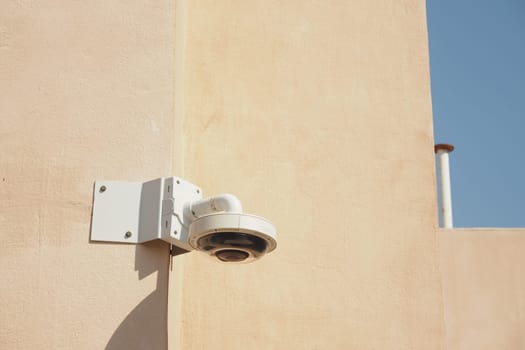 A high-resolution security camera is attached to a light-colored wall.