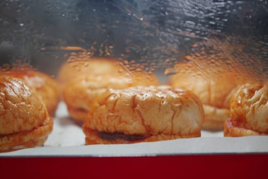 Delicious pastries are showcased under glass at a bustling market.