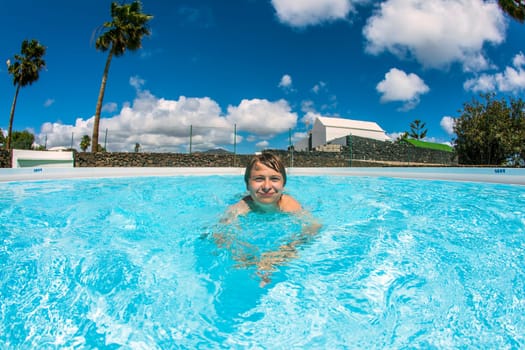 cute boy swimming in the blue pool
