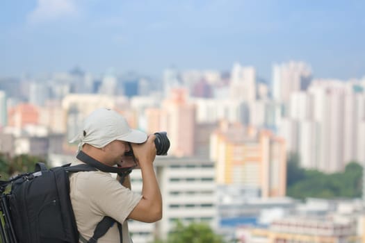 Photographer with digital camera taking photo of modern city