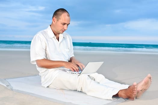Freelancer working on the tropical beach by laptop.