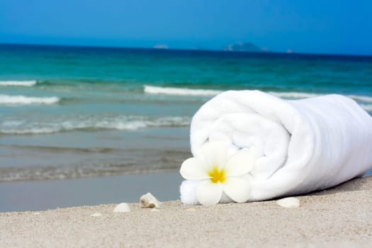 Spa still-life. Towel and plumeria flower on the tropical beach