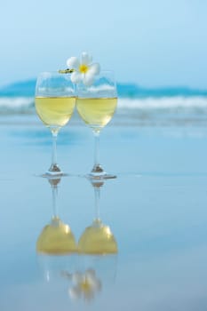Reflection of two glasses of white wine on tropical beach