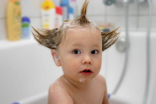 Child bathes with funny foam hairstyle