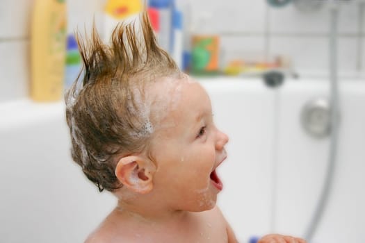 Child bathes with funny foam hairstyle
