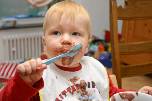 Little child eating chocolate pudding