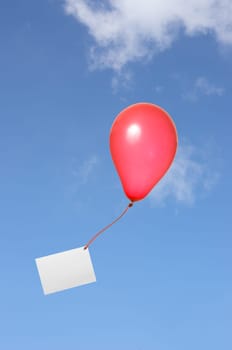Red balloon with greeting card against blue sky