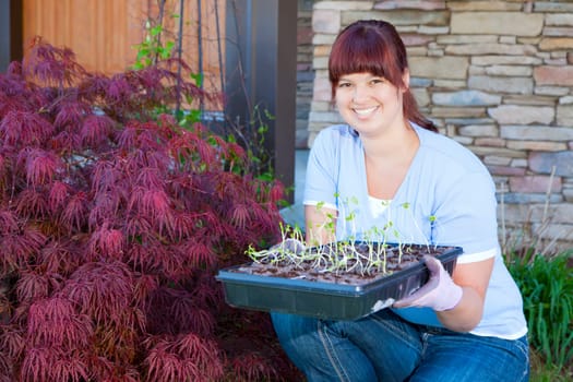 A young woman displays a tray of seedlings for her vegetable garden