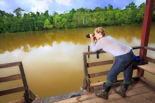 Young woman with camera. Expedition to lake.