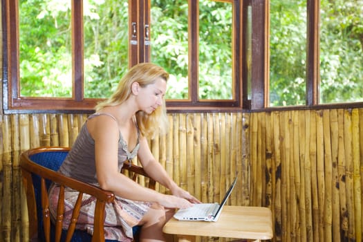 Young woman with laptop in bamboo house