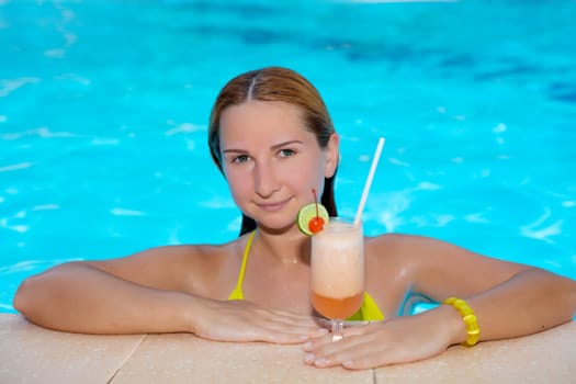 Woman wth moktail relaxing in swimming pool