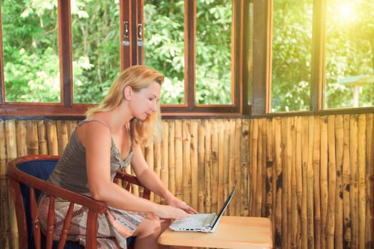 Young woman with laptop in bamboo house
