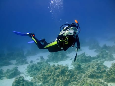 Diver with camera in deep and bubbles. Underwater photographer