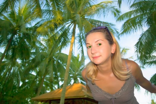 Wide angle portrait of woman on palm tree background.