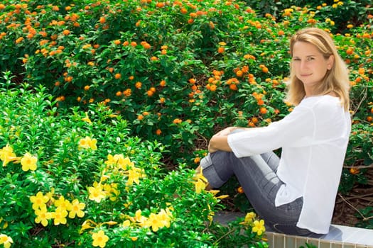 Young woman sitting in tropical flower garden