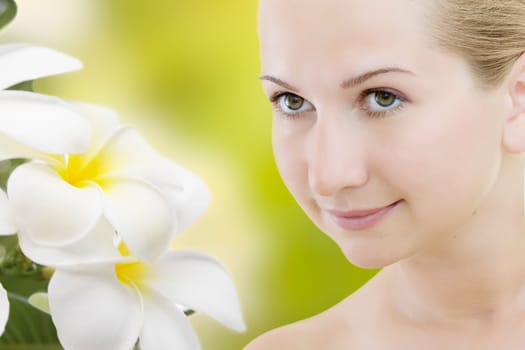 Close-up of beautiful woman face with plumeria flowers.