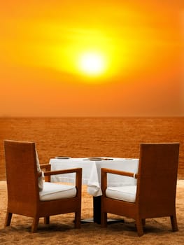 Dining table on white sand beach close to the ocean