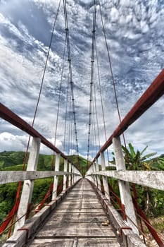 Wooden suspended bridge over mountain river. Vietnam