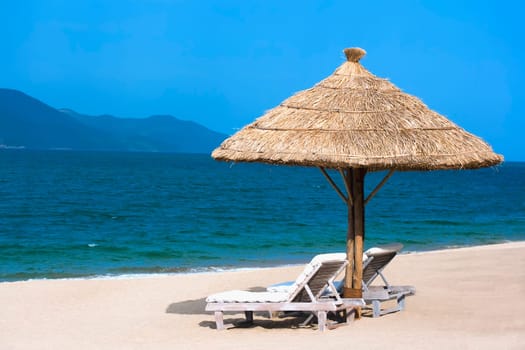 Two beach chairs on white sandy tropical beach