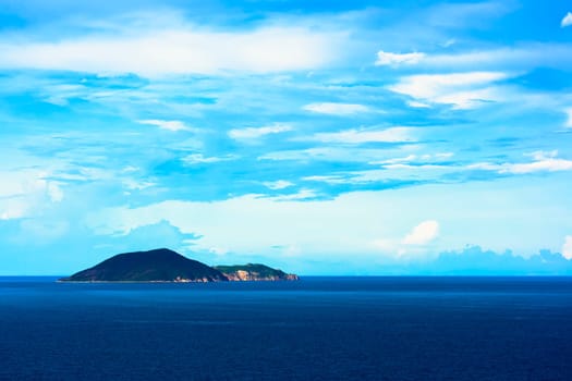 Tropical island. Blue ocean and cloudy sky background