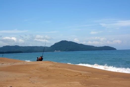 Fisherman with his son on the sandy beach of the ocean