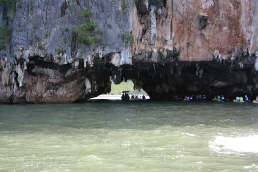 Tourists on a canoe in a cave under a rock in the ocean.  Ao Phang nga National Park