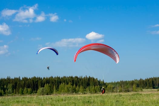 Two paragliders with red and blue wings