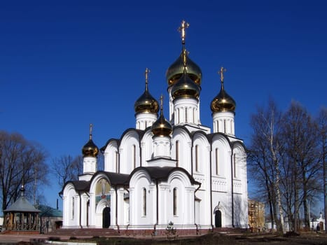 Christian church with the gilt domes on a background of the blue sky