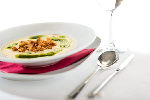 Creamy soup with garlic, spinach and croutons in white plate