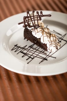 Sacher cake with whipped cream and chocolate on cocoa background
