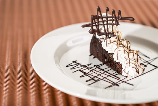 Sacher cake with whipped cream on chocolate background